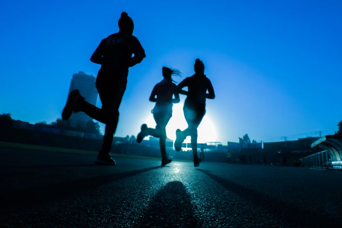 Three runners silhouetted against the evening sky