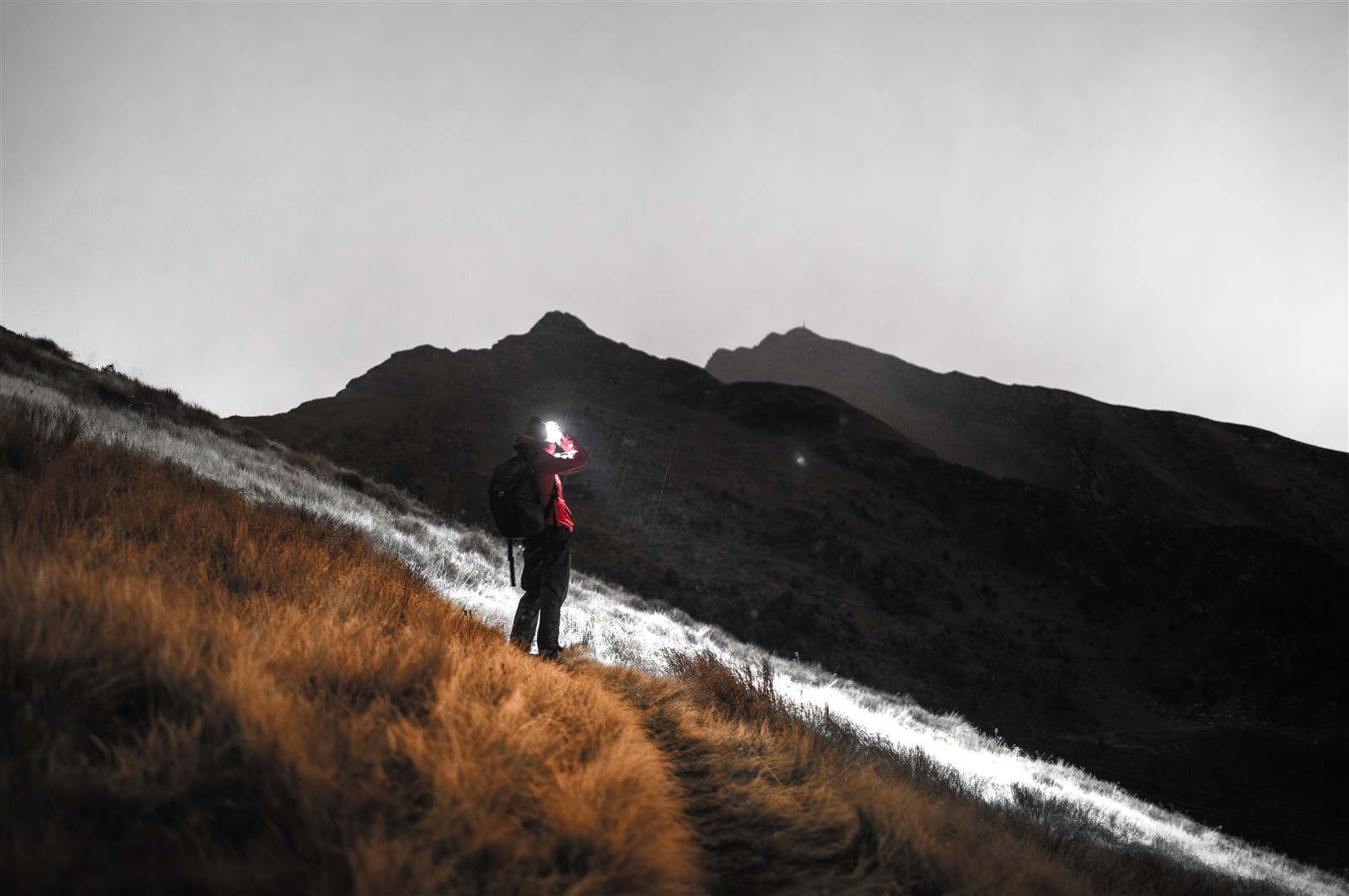 Hiker using a headtorch on a mountain path at night